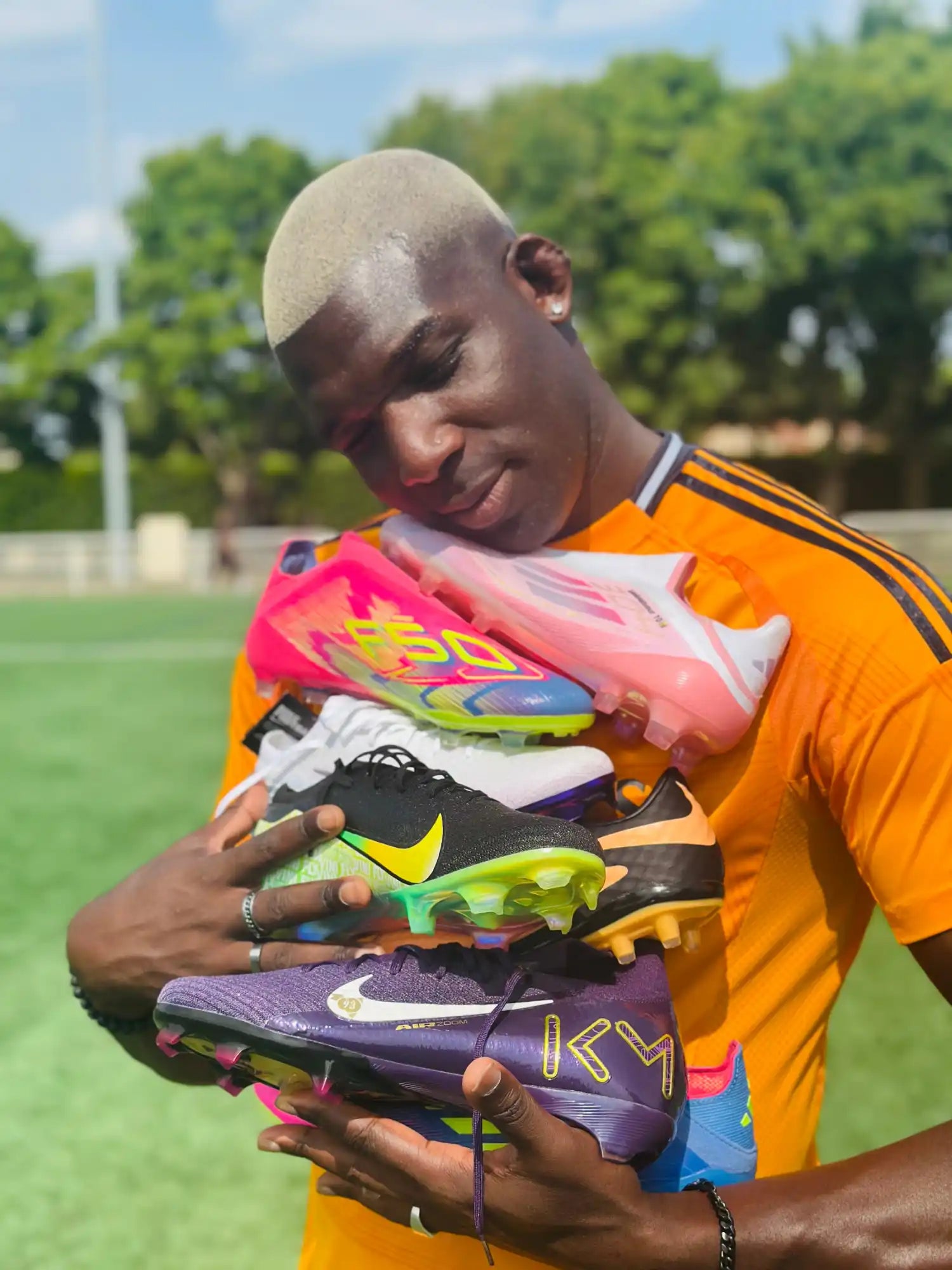 Un homme tenant cinq paires de crampons de football vibrants.